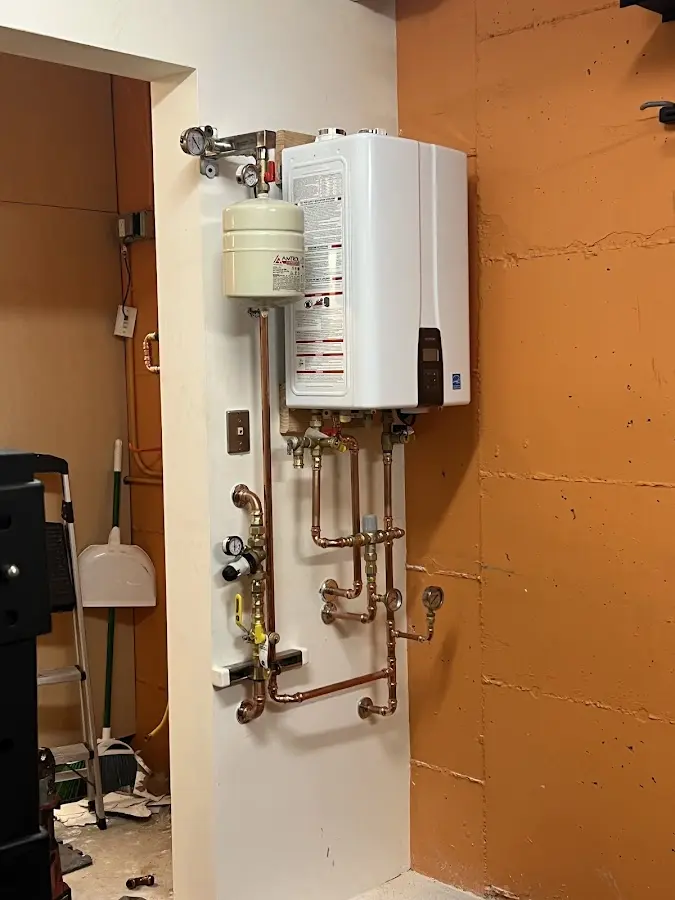 Plumbing technician inspecting water heater connections in Collinsville